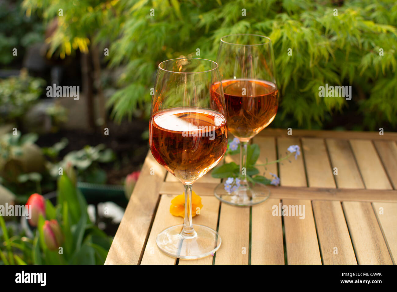 Zwei kalte rose Weingläser auf der Terrasse im Garten mit Blumen im  sonnigen Tag Stockfotografie - Alamy