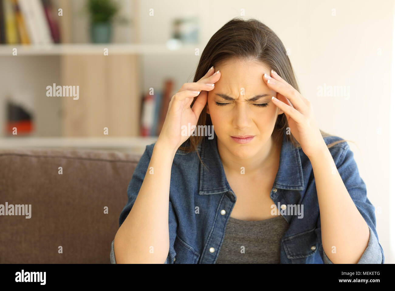 Vorderansicht Porträt einer Frau beschweren leiden Migräne auf einer Couch im Wohnzimmer zu Hause sitzen Stockfoto