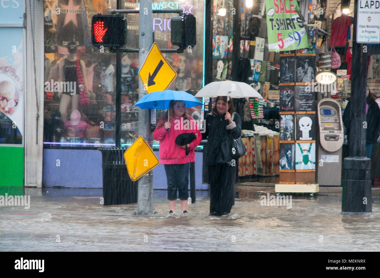 HOLLYWOOD - Januar 21, 2018: Nicht identifizierte Frauen versuchen, die Straße auf schweren regnerischen Tag zu Kreuzen in der Stadt Hollywood, CA. Stockfoto