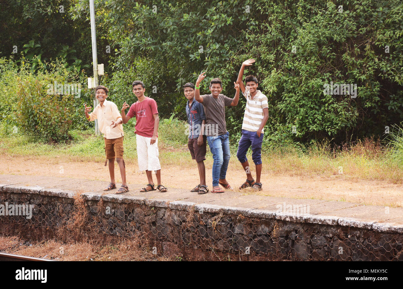 Gruppe junger Männer auf einem Bahnsteig in Indien zu einem vorbeifahrenden Zug Stockfoto