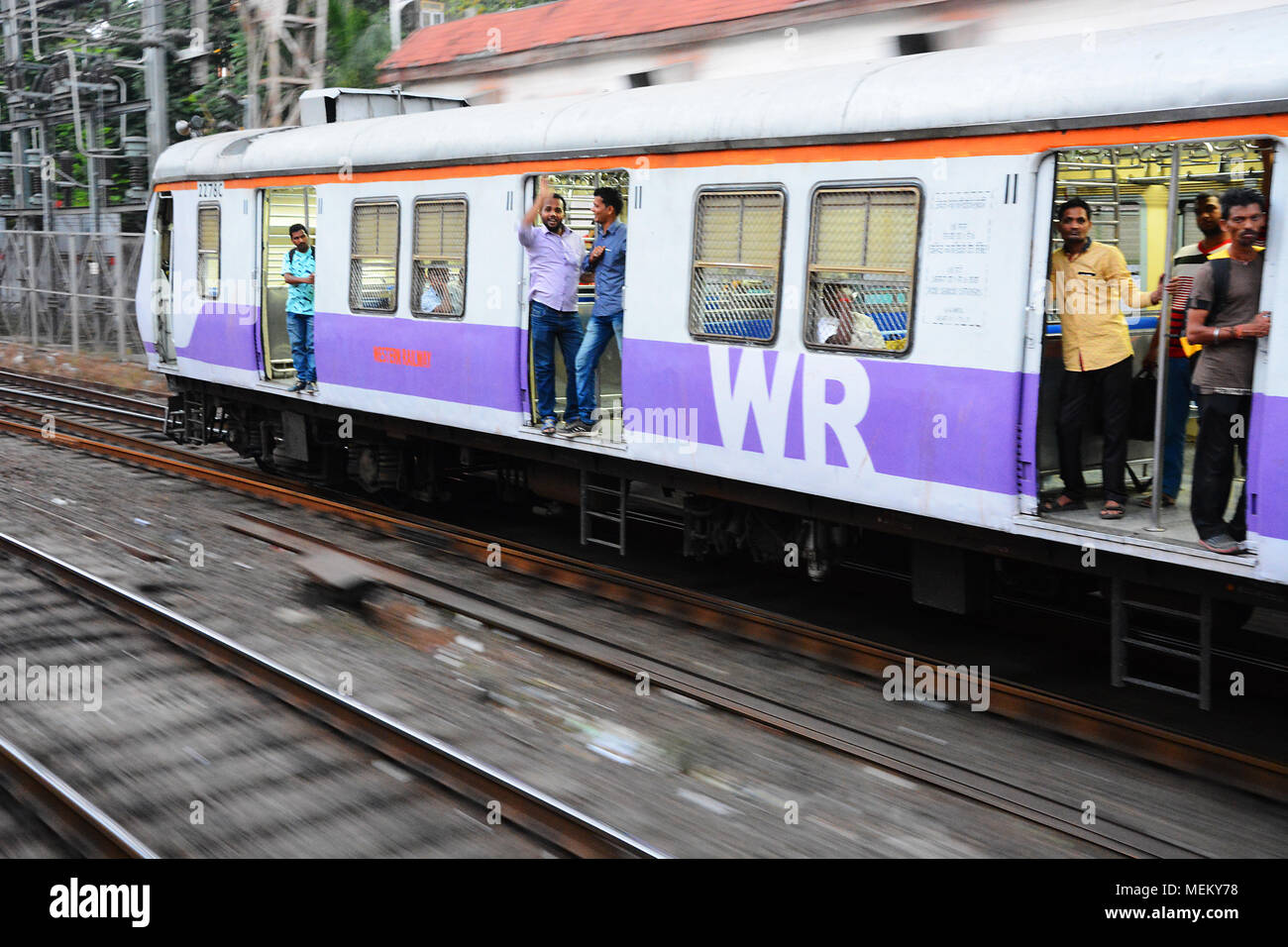 Männliche Passagiere auf einen anderen Zug winken in sehr freundlich zu uns, als wir uns durch, Mumbai, Indien Pass Stockfoto