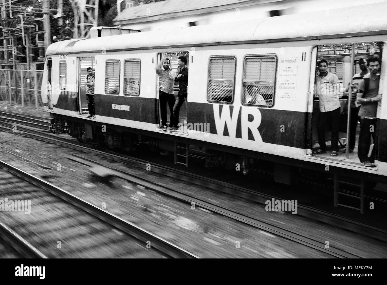 Männliche Passagiere auf einen anderen Zug winken in sehr freundlich zu uns, als wir uns durch, Mumbai, Indien Pass Stockfoto