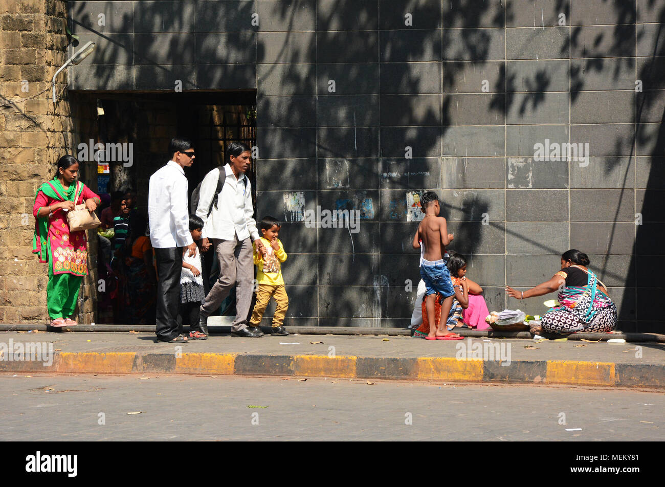Familie Gruppe sitzen auf dem Fußweg auf einer Straße in Mumbai, Indien Stockfoto