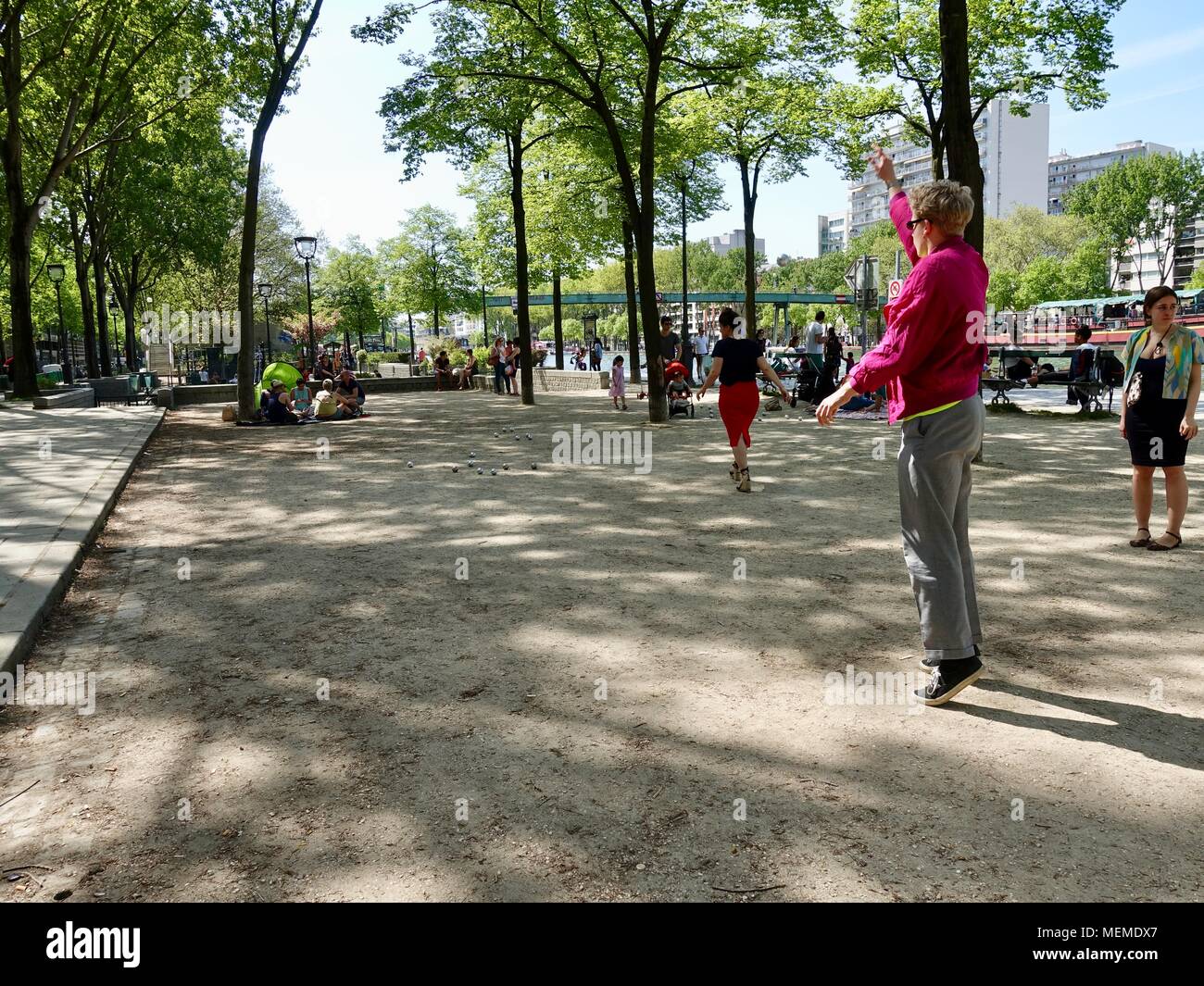 Menschen spielen Pétanque im Schatten neben dem Kanal auf einem warmen, April Nachmittag. Bassin de la Villette, Paris, Frankreich. Stockfoto