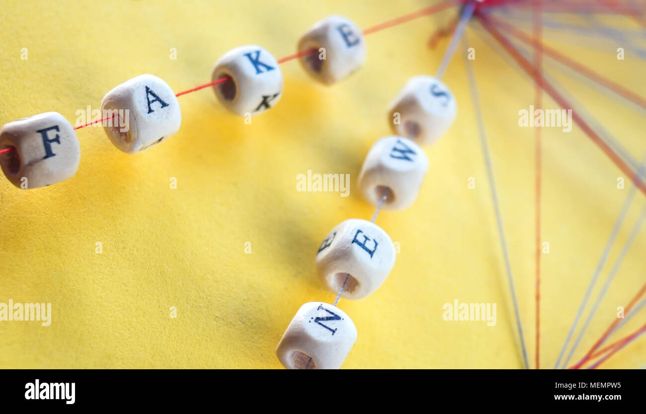 Beschriftete Perlen von Seil und Nägel auf gelben Hintergrund Visualisierung gefälschte Nachrichten im Netzwerk Stockfoto