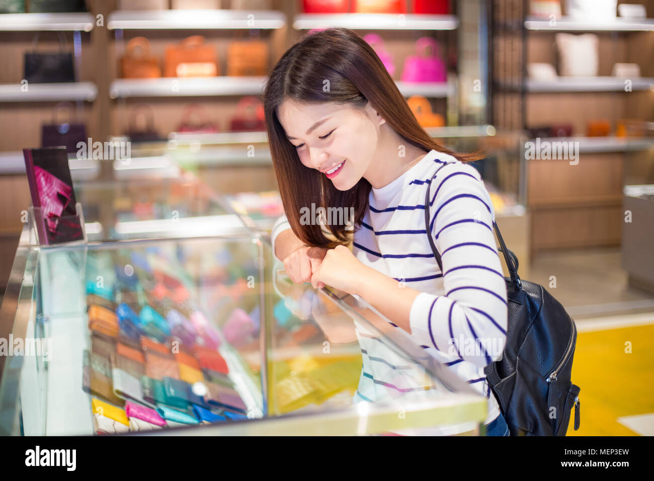 Glückliche junge attraktive asiatische Frau Shopping und Merchandising in glas Vitrine in einem Geschäft entscheiden, in welches man kaufen Stockfoto