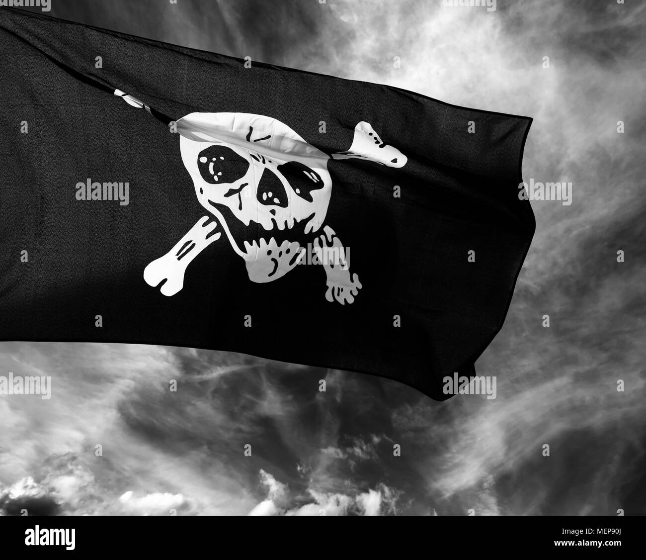 Schwarze und weiße Jolly Roger (Pirate flag) gegen Gewitterwolken Stockfoto