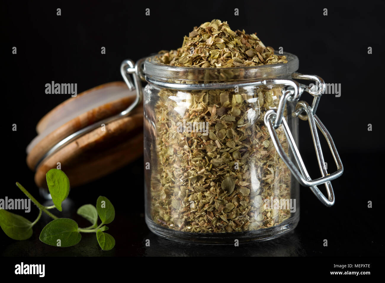 Glas Glas mit getrockneten Oregano über Dunkle Schiefer Hintergrund Stockfoto