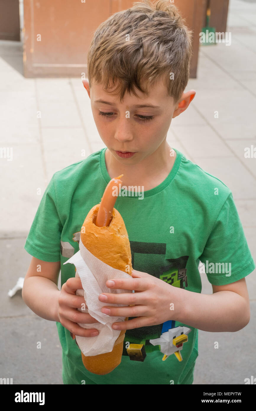 Acht Jahre alten Jungen mit einem Hot Dog Würstchen Wiener Würstchen auf wurstl Graben Straße Wien Österreich Europa ausgeht. Stockfoto
