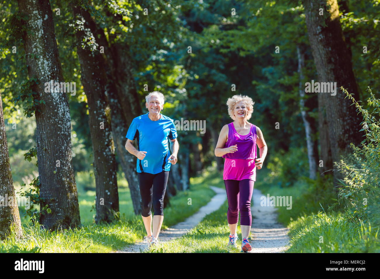 Zwei aktive Senioren mit einem gesunden Lebensstil Lächeln beim Joggen Stockfoto
