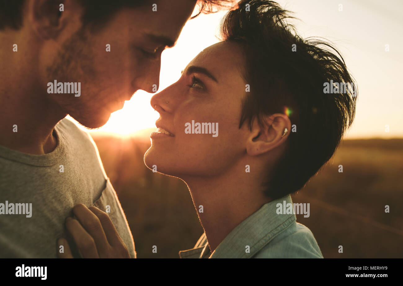 Frau mit der Mann in der Nähe von ihr, während sie ihm in die Augen, ein romantisches im freien Stellen suchen. Stockfoto
