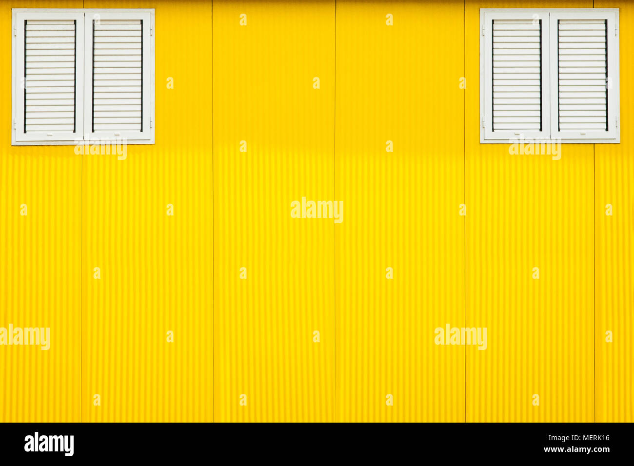 Die beiden Fenster Fensterläden auf Gelb sonnigen Wand gesperrt. Stockfoto