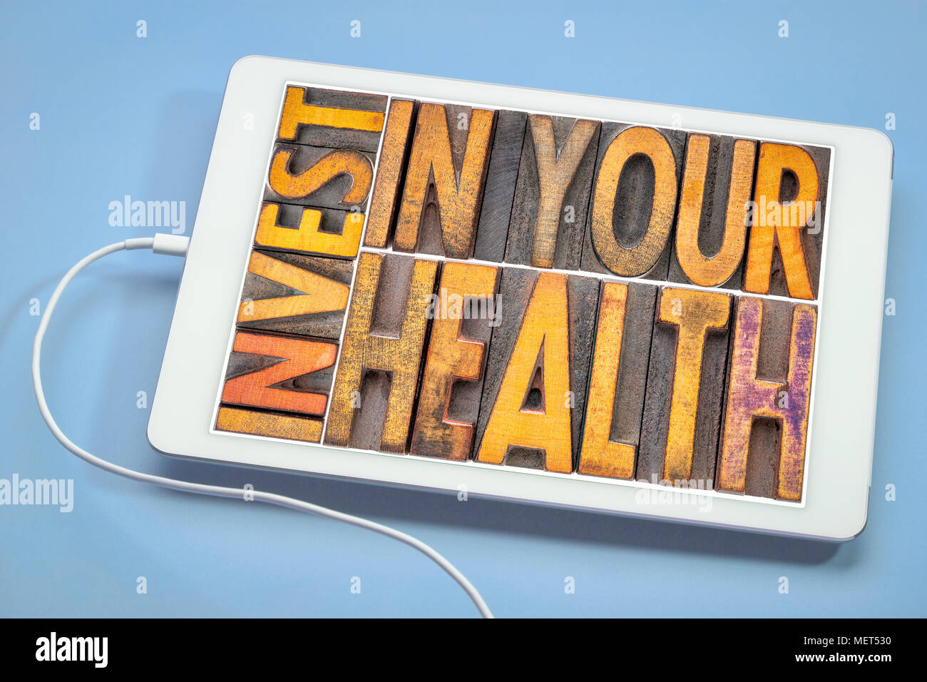 Konzept investieren Sie in Ihre Gesundheit - Wort in Vintage buchdruck Holz Art Abstract auf einer digitalen Tablet Stockfoto