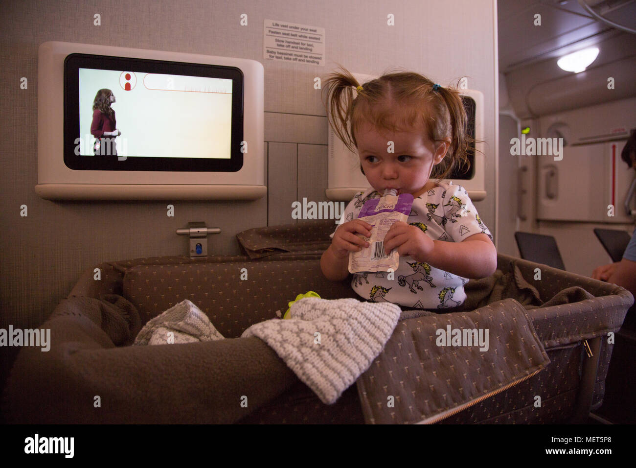 14 Monate altes Mädchen sass in der Wiege auf Singapore Airlines Flug Stockfoto