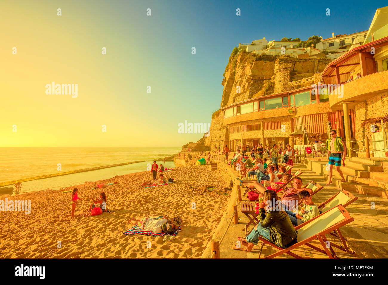 Azenhas do Mar, Portugal - August 5, 2017: Touristen Sonnenbaden und Relaxen am berühmten Strand von Azenhas do Mar in Colares, Atlantische Küste, mit seinen natürlichen Pool bei Ebbe sichtbar. Sonnenuntergang Sonnenlicht. Stockfoto