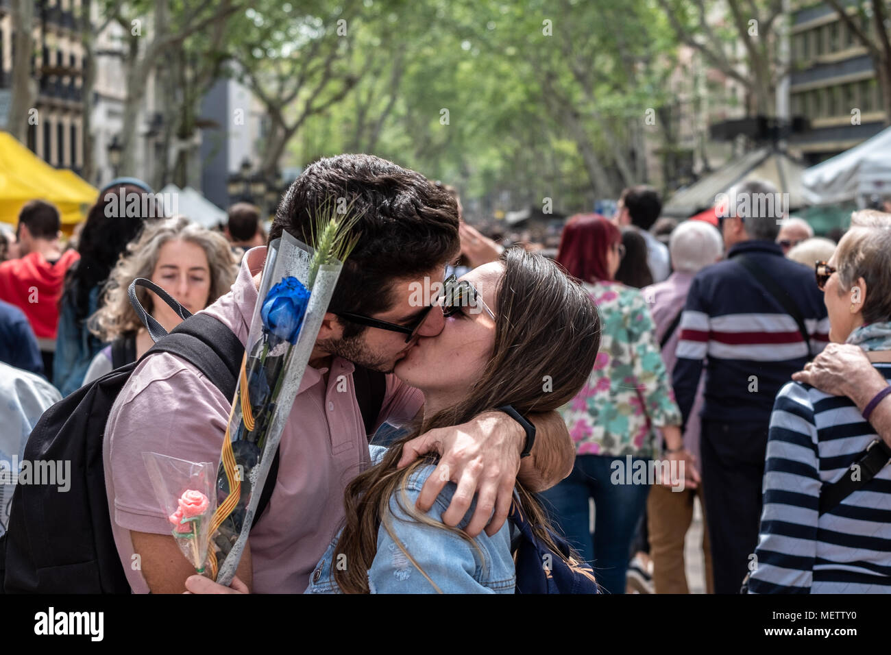 Barcelona, Spanien. 23. April 2018. Ein paar gesehen wird, während in der Mitte der Ramblas in Barcelona zu küssen. Catalunya feiert den "Tag des Sant Jordi", dem Tag der Bücher und Rosen. Catalunya hofft zu erreichen, die Zahl von 7 Millionen Rosen verkauft. Es ist Tradition eine Rose oder ein Buch bei Liebhabern zu geben. Zahlreiche literarische Autoren signieren ihre Bücher der Öffentlichkeit auf die Straße. Credit: SOPA Images Limited/Alamy leben Nachrichten Stockfoto