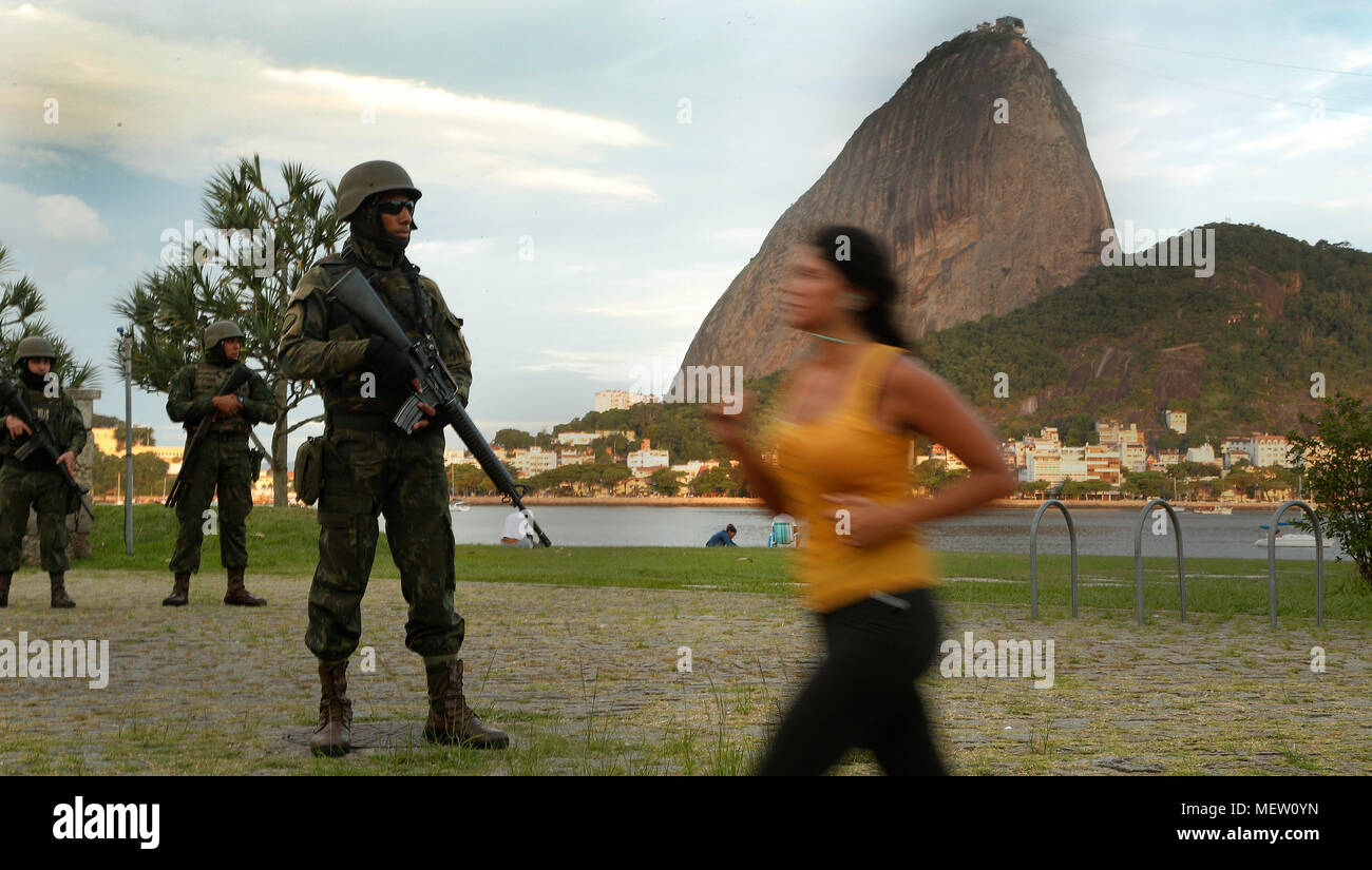 Rio de Janeiro, Brasilien. April 23rd, 2018 eine brasilianische Armee Soldat sichert einen touristischen Stelle vor den Zuckerhut Hügel als lokaler Bewohner läuft. Credit: Antonio Di Paola/Alamy leben Nachrichten Stockfoto