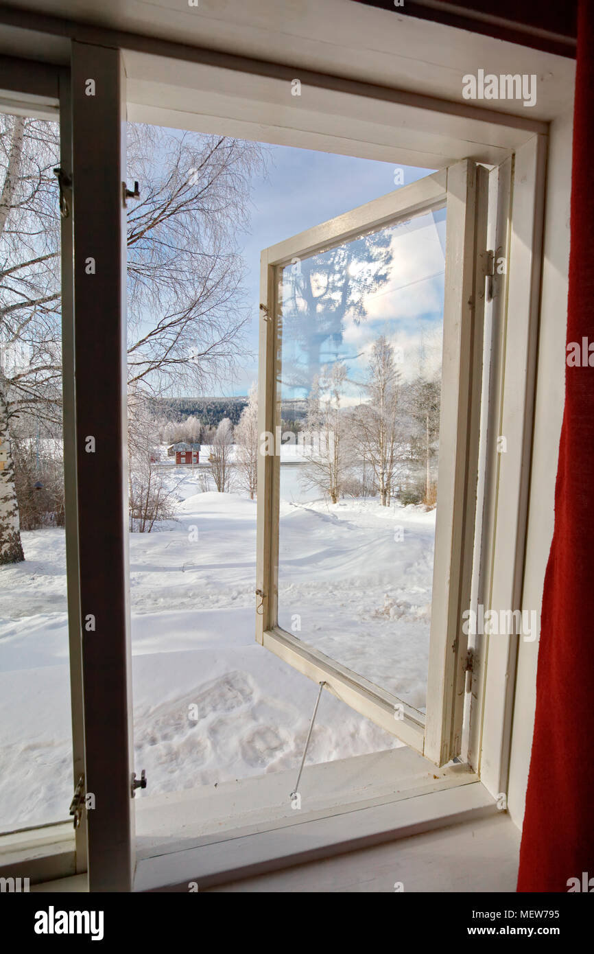 Ein Fenster zu einem schneebedeckten Garten an einem sonnigen Wintertag geöffnet. Stockfoto