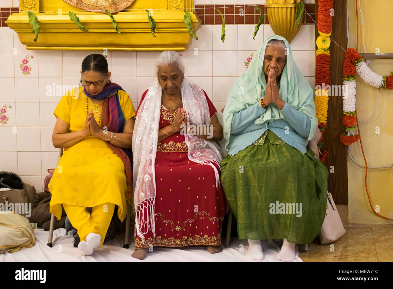 Drei hinduistischen Frauen beten und meditieren in der Shri Lakshmi Narayan Mandir Hindutempel in Richmond Hill, Queens, New York. Stockfoto