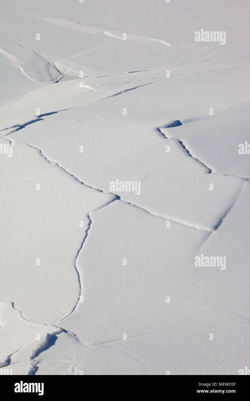 Risse erscheinen in den schneebedeckten Eis auf einem See Stockfoto