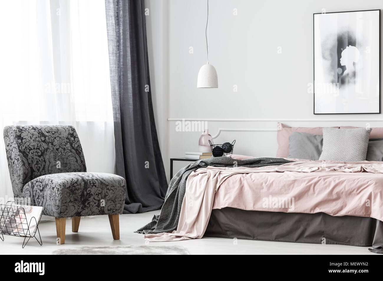 Helle elegante Hündin Schlafzimmer Innenraum mit pastellfarbener Bettwäsche und grauen Sessel Stockfoto