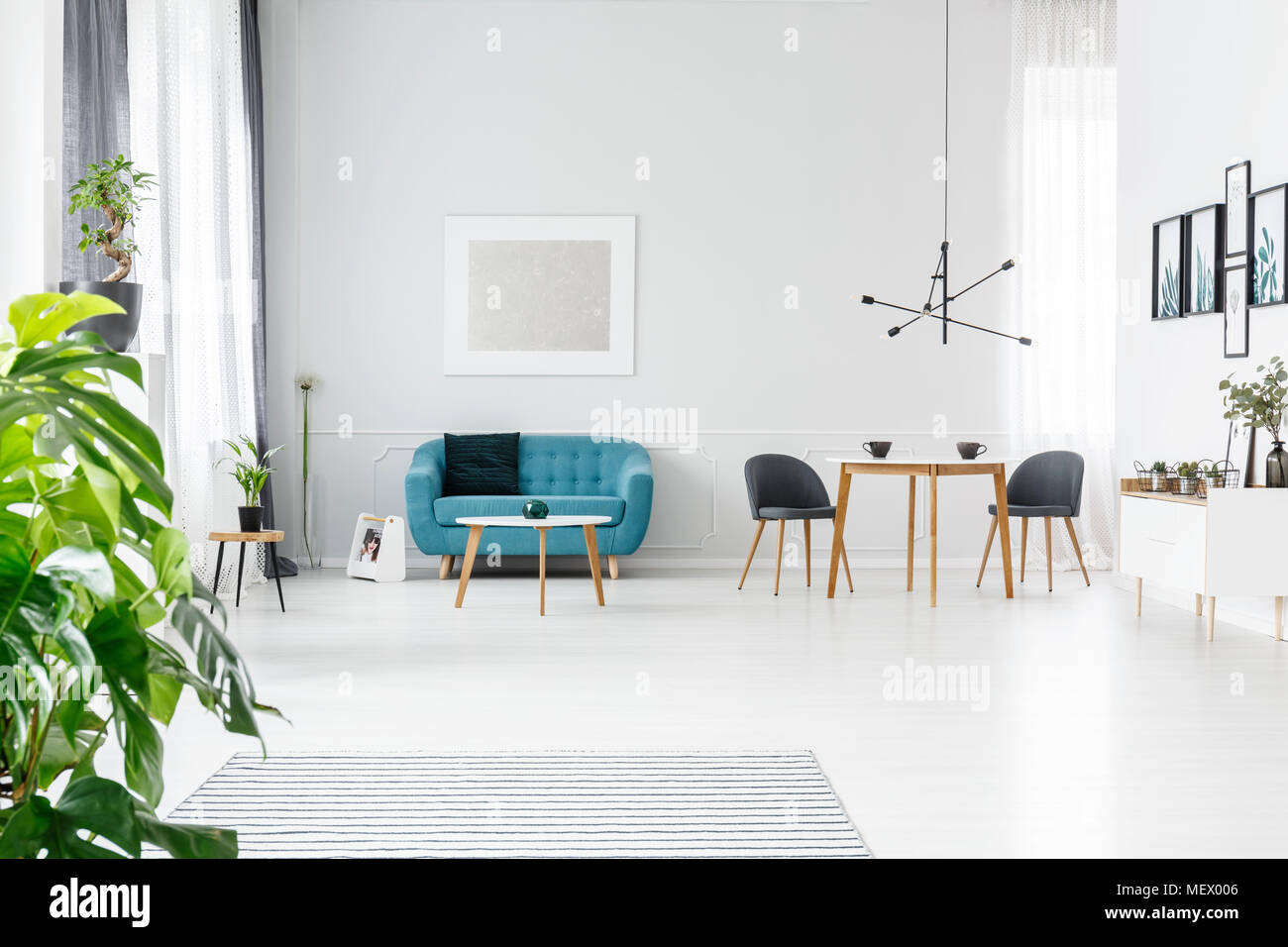 Helle, geräumige und elegante Wohnung zum Verkauf mit Plakaten, Kaffeetassen auf Holztisch und Türkise couch Stockfoto