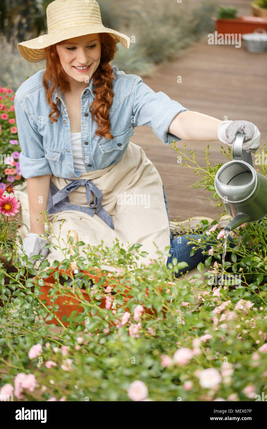 Lächelnd Gärtner Frau Blumen gießen im Garten Stockfotografie