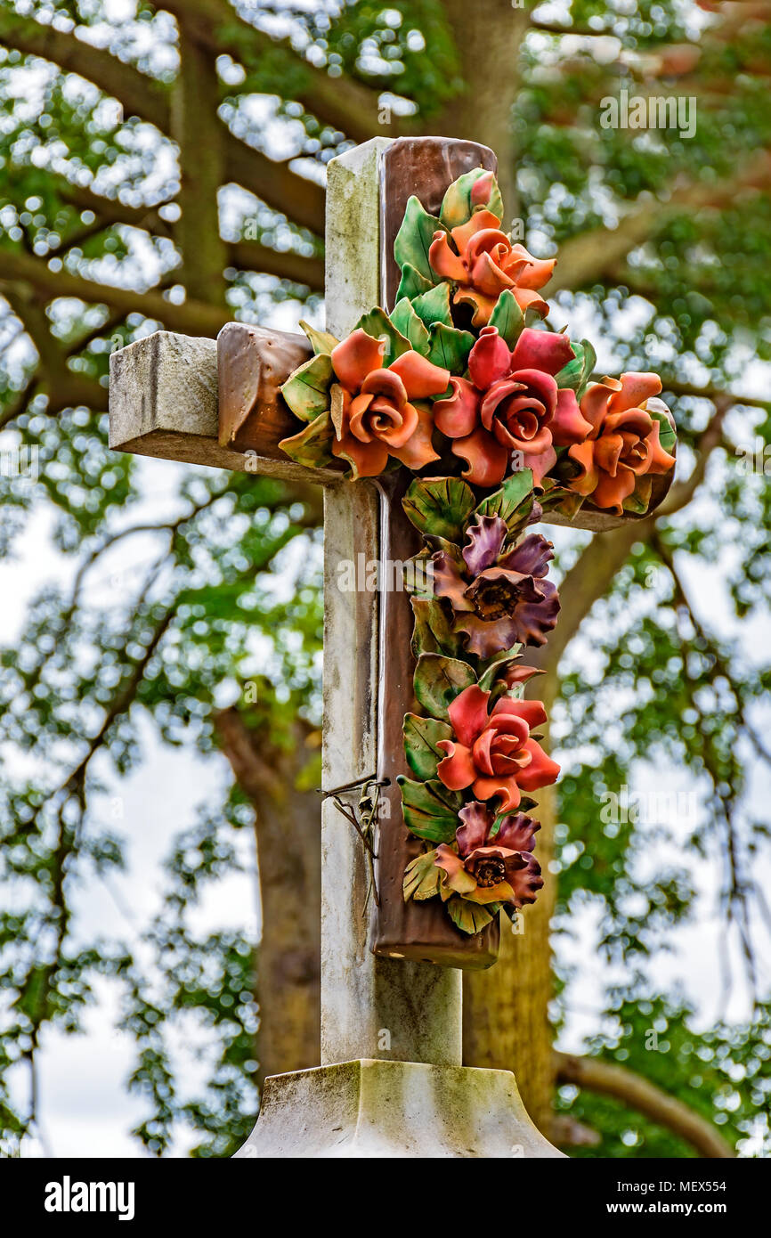 Altes steinernes Kruzifix geschmückt mit Blumen im historischen Friedhof an einem der berühmten Kirchen der Stadt Ouro Preto in Minas Gerais, Brazi Stockfoto