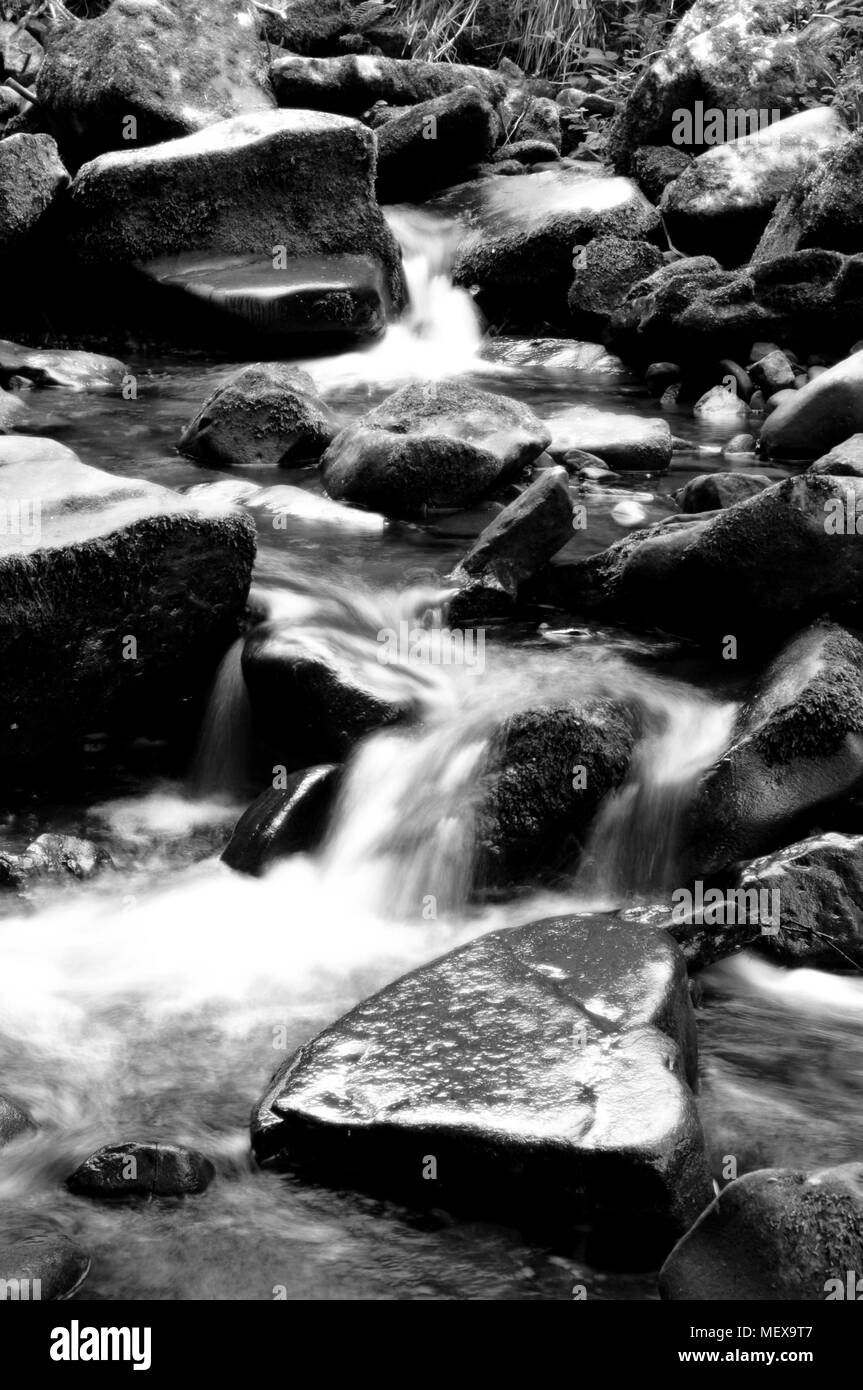 Wasser fließt durch einen Berg Rock in Schwarz und Weiß riverbed Beschlagenen Stockfoto