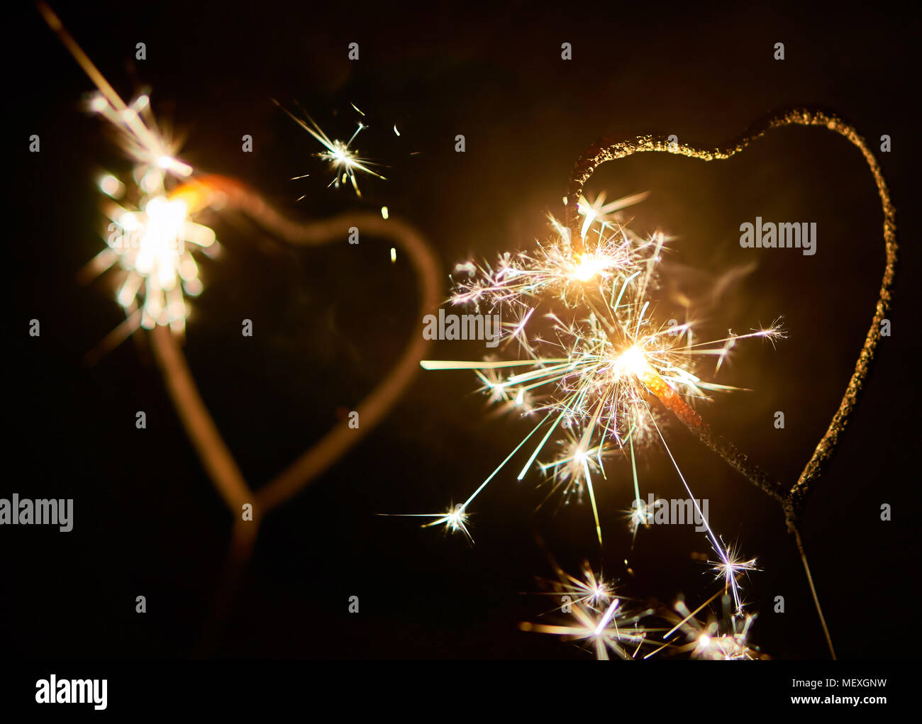 Zwei bengalischen Lichter in der Form eines Herzens brennen hell auf dunklem Hintergrund - Valentinstag Symbol Stockfoto