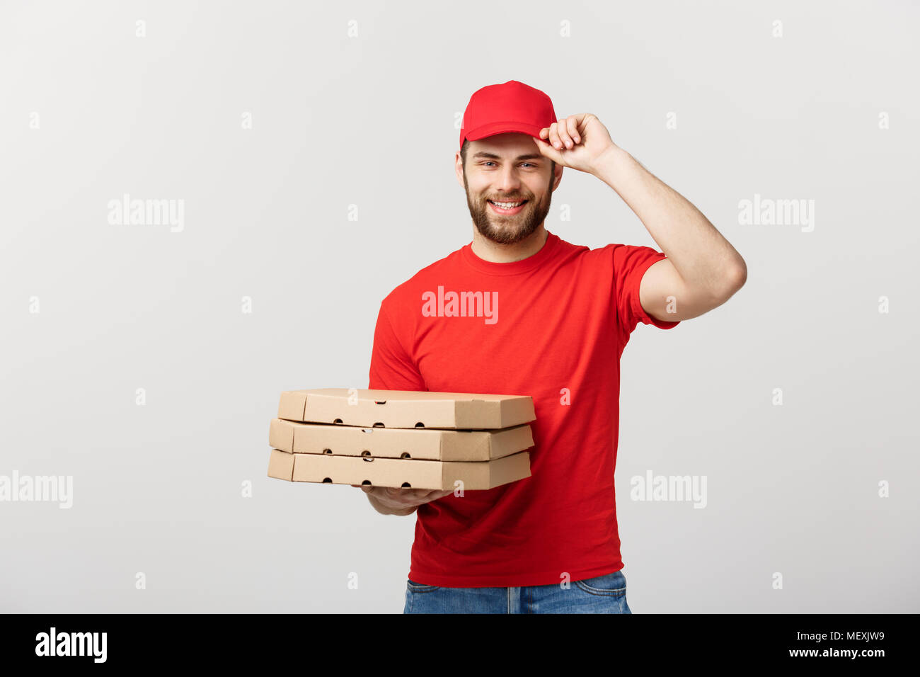Lieferung Konzept: jungen kaukasischen stattlichen Pizza Delivery Man holding Pizzakartons über grauer Hintergrund Stockfoto
