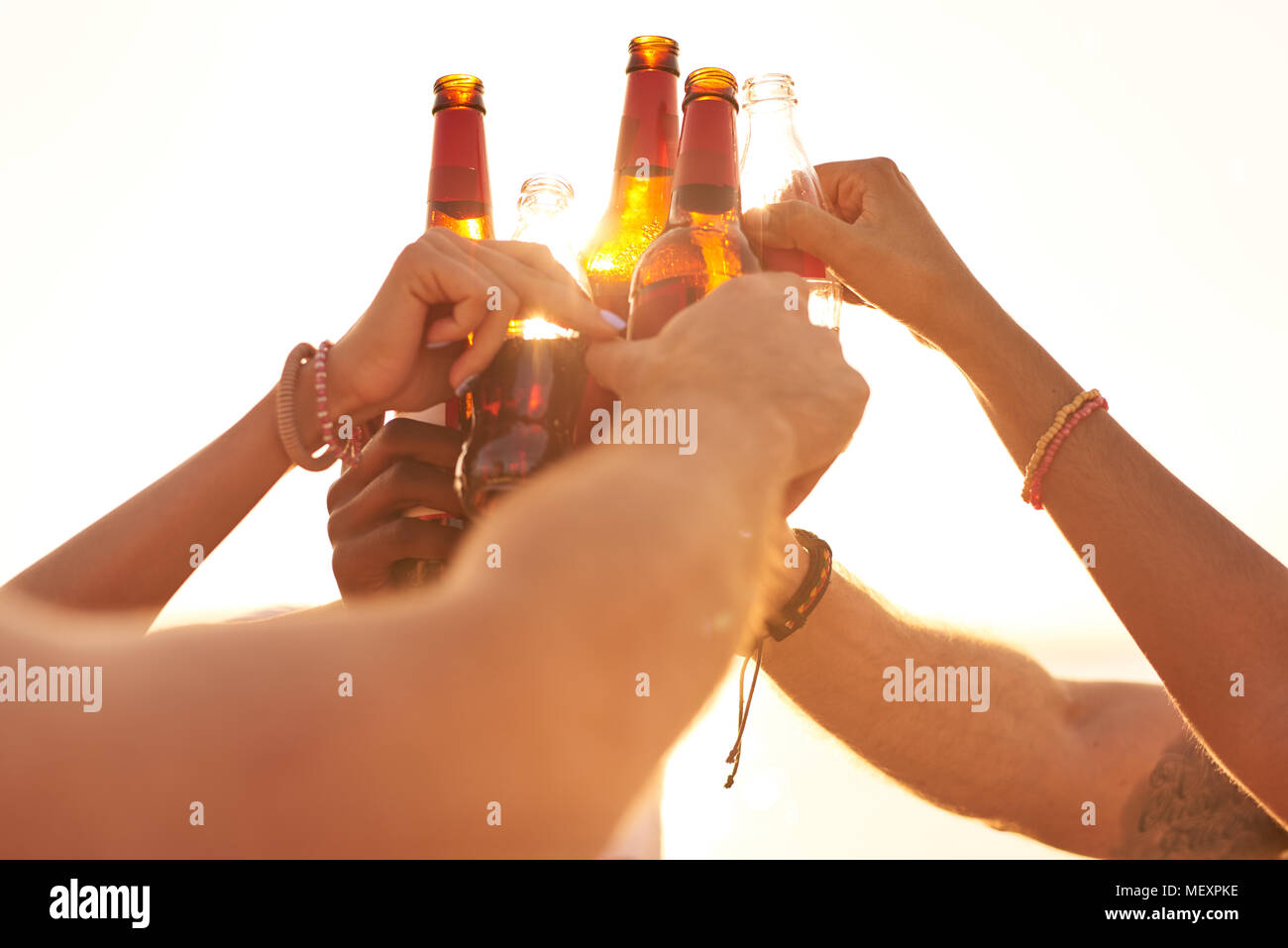 Freunde klirren Bierflaschen im Sonnenlicht Stockfoto