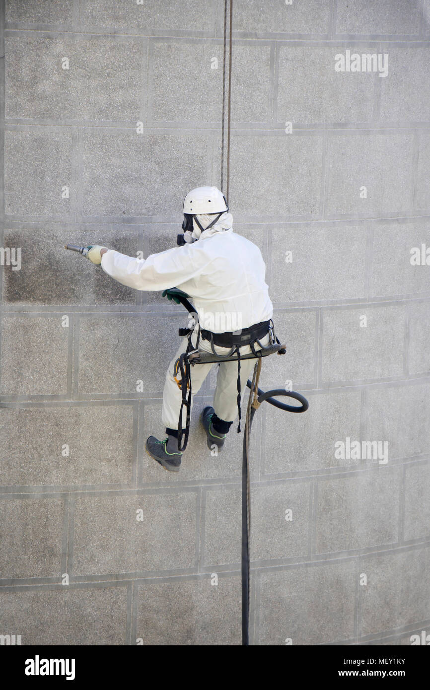 Zugang mit Seil Fassade Wartung; ein Arbeiter tragen einer Schutzausrüstung Reinigung eine Steinfassade mit Sandstrahlanlage Stockfoto