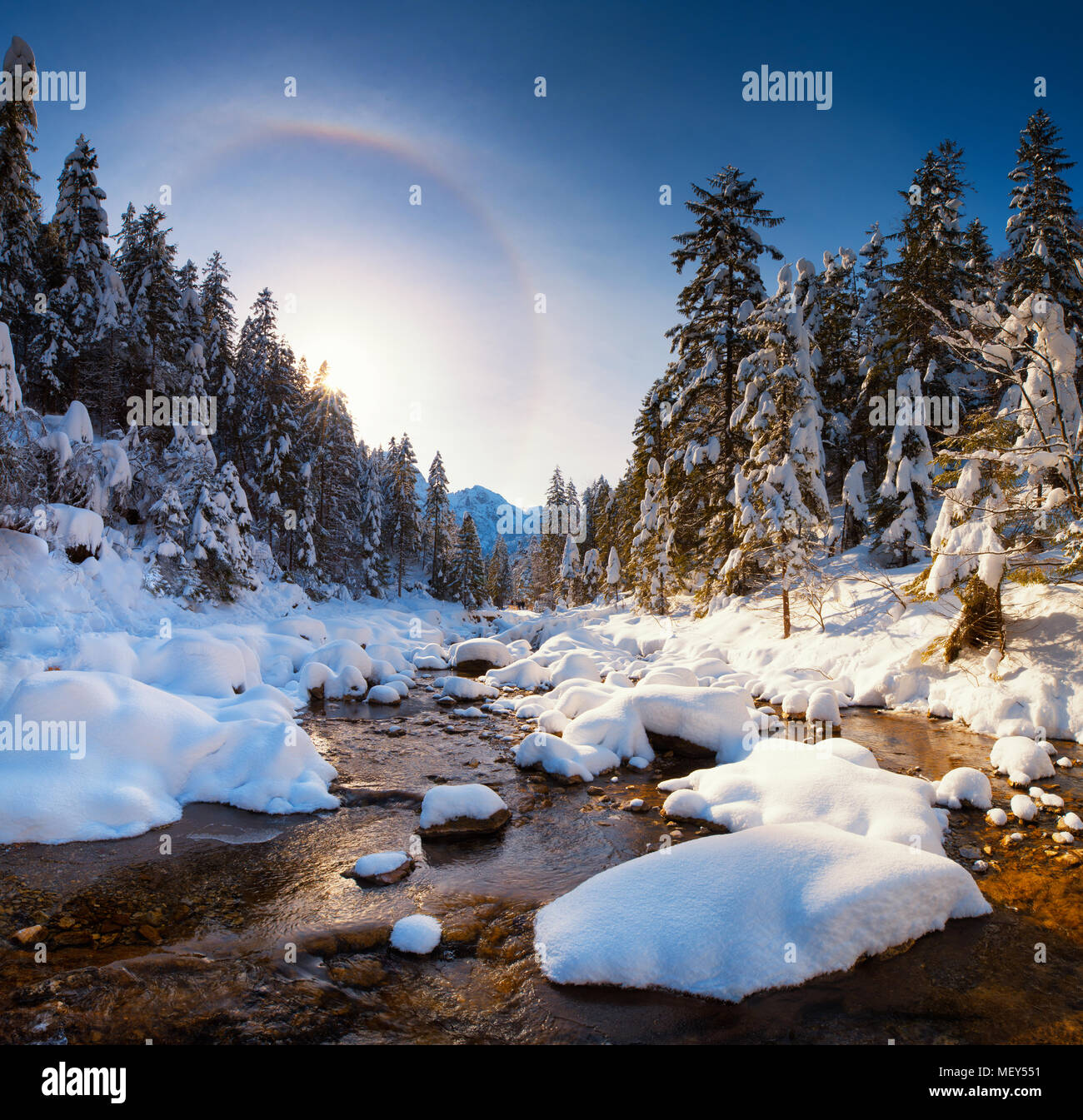 Erstaunlich Frühling Landschaft. Mountain Stream in Tatra Berge mit schneebedeckten Riverside. Halo Effekt in blue Clear Sky. Stockfoto