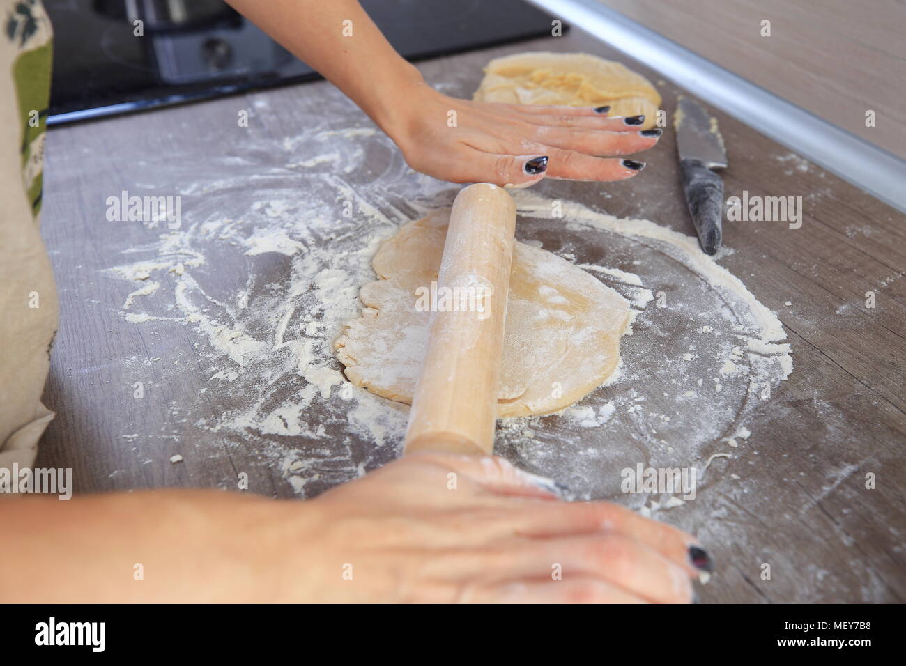 Holz- Rolling Pin in der Frau die Hände. Hausfrau Kochen Teig zu Hause. Stockfoto