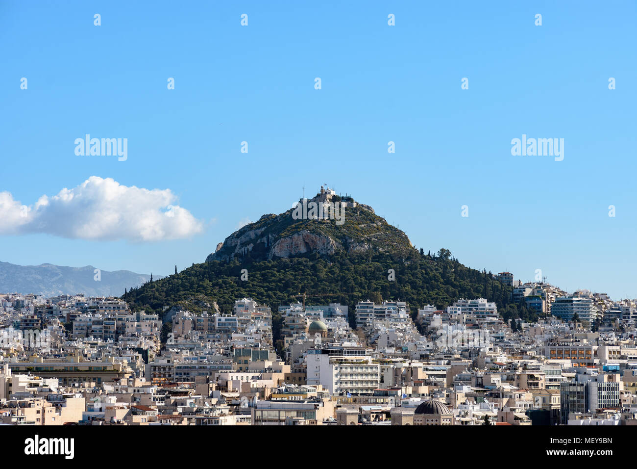 Mount Lycabettus durch Gebäude mit blauem Himmel und weißen Wolken als Hintergrund in Athen, Griechenland, während der sonnigen Tag am Morgen umgeben. Stockfoto