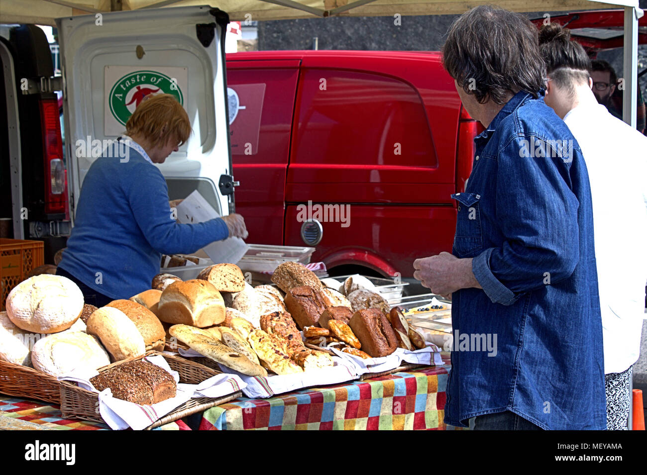 Essen Marktstand Inhaber Verkauf von frischem Brot für die Kunden in der Warteschlange, der Wochenmarkt ist in skibbereen Irland ein beliebtes Touristenziel Stockfoto