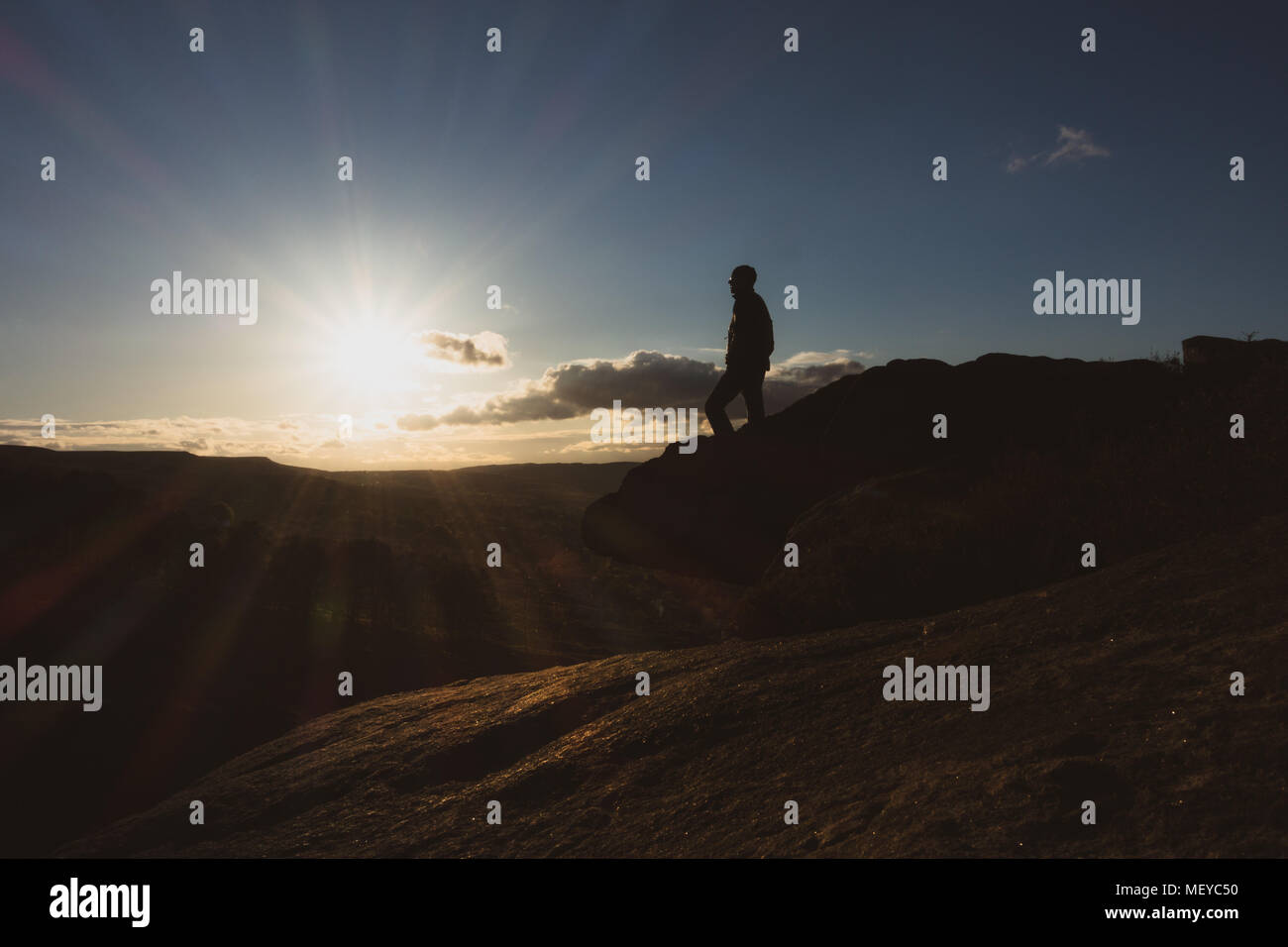 Mann stand am Rande einer Klippe (Crocodile Rock on Ilkley Moor) den Sonnenuntergang beobachten, Großbritannien Stockfoto