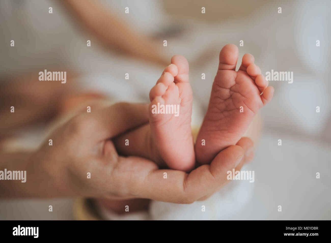 Mutter halten Sie die Füße des neugeborenen Babys. Hautpflege. Stockfoto