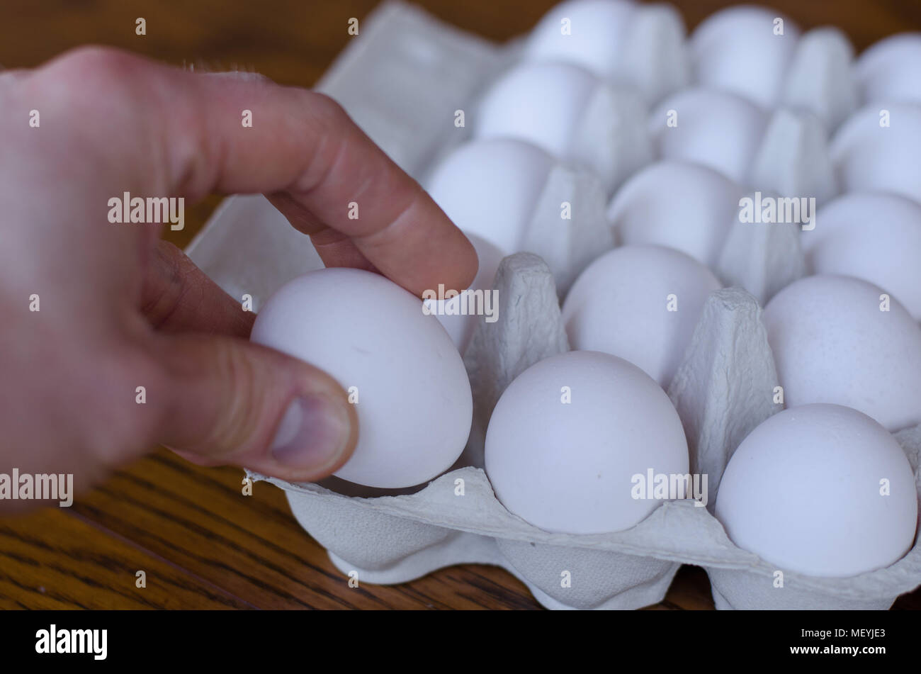Ein Ei unter einer Gruppe von Eiern, die von einer Hand abgeholt werden Stockfoto