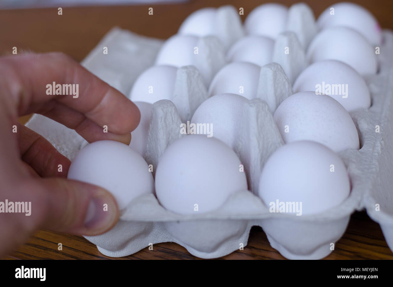 Ein Ei unter einer Gruppe von Eiern, die von einer Hand abgeholt werden Stockfoto