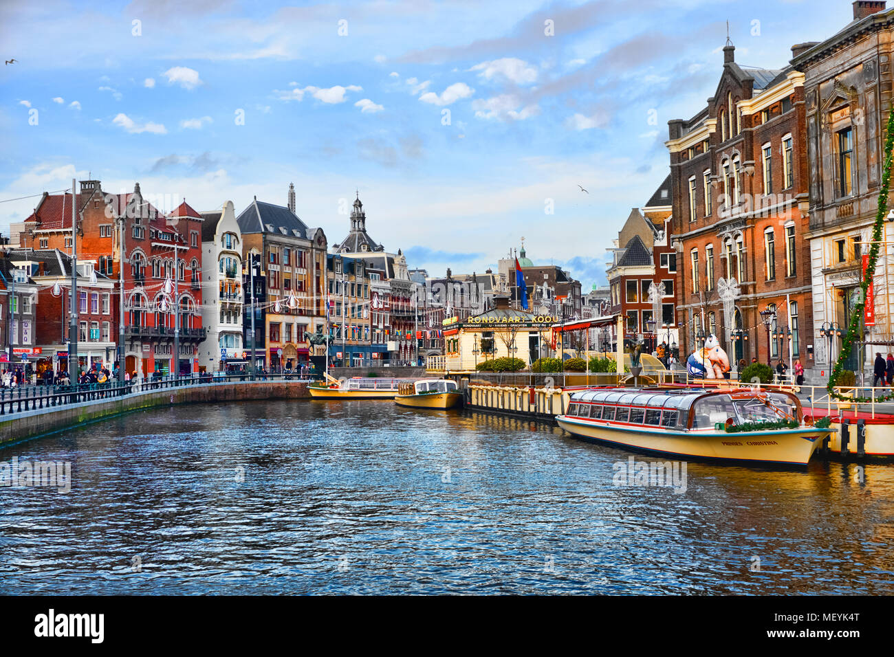 AMSTERDAM, NIEDERLANDE - 1. JANUAR 2018: Malerische Aussicht auf das Stadtzentrum von Amsterdam an sonnigen Tag nach Weihnachten. Canal touristische Boote sind festgebunden. Stockfoto