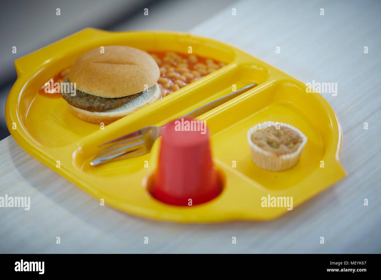 Eine Schule Abendessen Fach mit Burger, Bohnen, Kuchen und Getränken Stockfoto