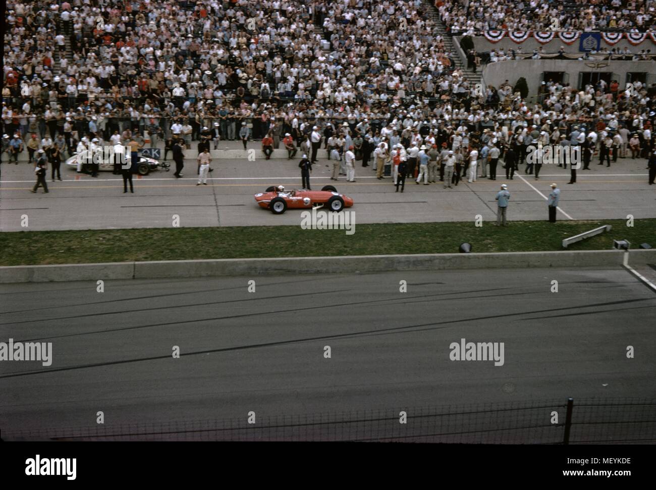 Rennwagen und Zuschauer werden an den Indianapolis 500 Automobil Rennen in Indianapolis Motor Speedway in Indianapolis, Indiana, 1965 sichtbar. () Stockfoto