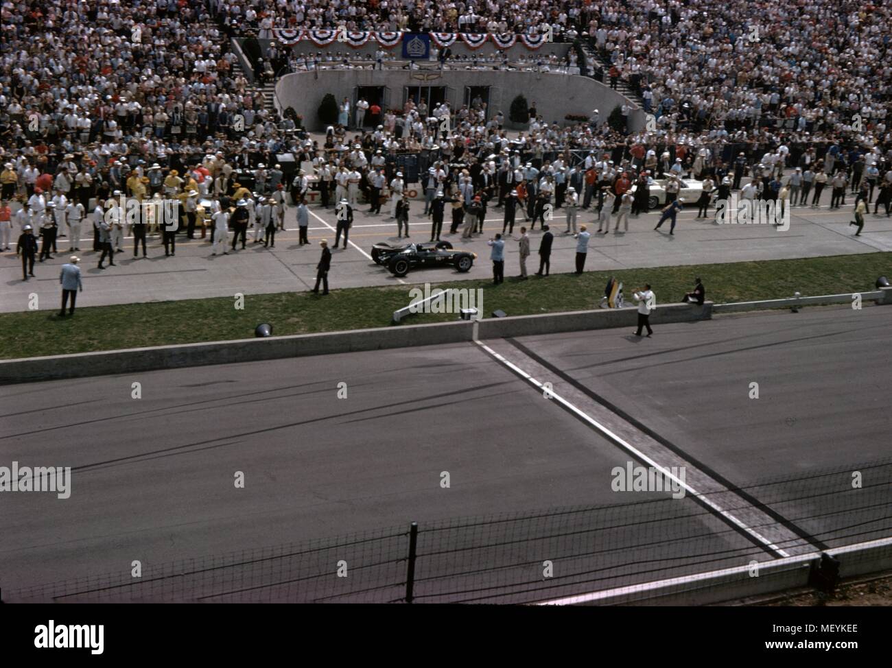 Rennwagen und Zuschauer werden an den Indianapolis 500 Automobil Rennen in Indianapolis Motor Speedway in Indianapolis, Indiana, 1965 sichtbar. () Stockfoto