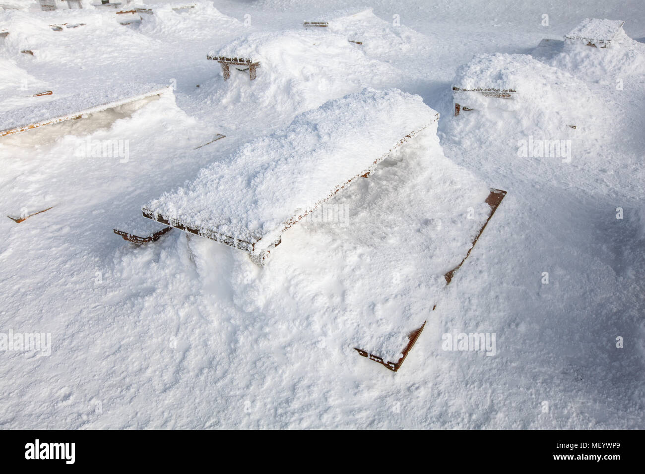 Holzbänke und Schreibtisch auf Restaurant Terrasse kaum unter der schweren Last des Schnee sichtbar. Konzept zur Veranschaulichung von extremer Schneefall. Stockfoto