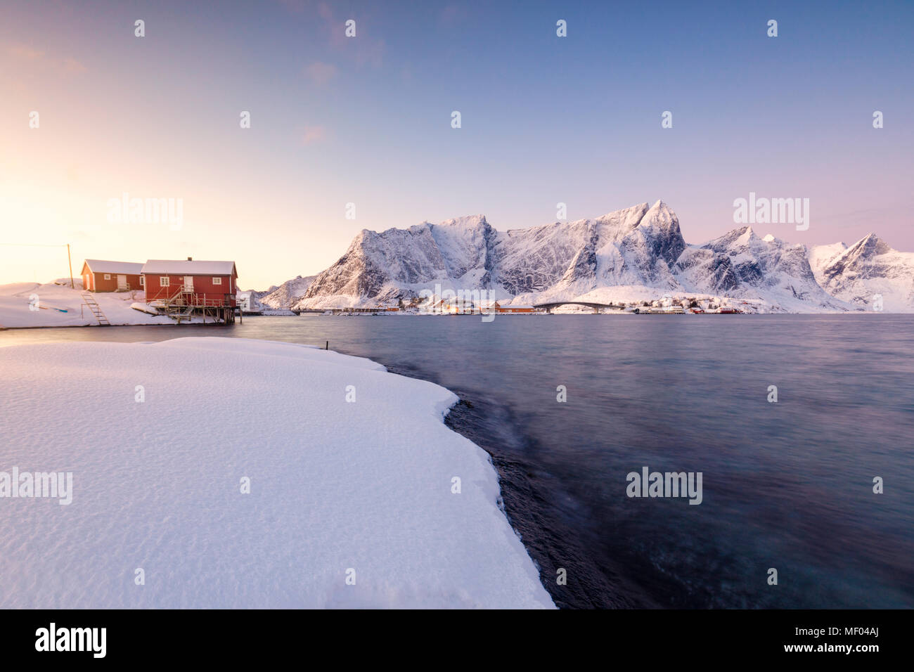 Die Farben der Morgenröte rahmt die Fischerhäuser, umgeben von gefrorenen Meer Sakrisøy Reine Nordland Lofoten Inseln Norwegen Europa Stockfoto