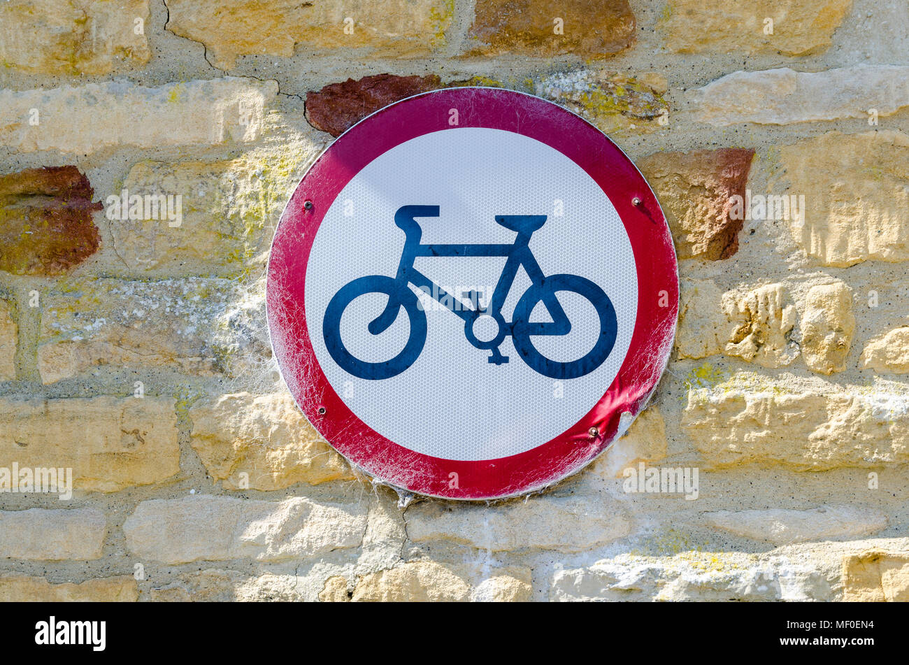 Keine radfahren oder Fahrräder Zeichen auf eine Mauer aus Stein, die in der hübschen Cotswold Dorf Lower Slaughter in Gloucestershire, VEREINIGTES KÖNIGREICH Stockfoto