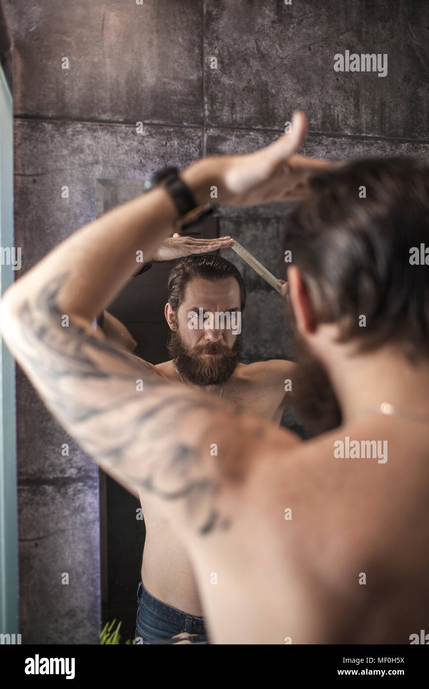 Portrait von bärtigen Mann mit Blick auf sein Spiegelbild, während seine Haare kämmen Stockfoto