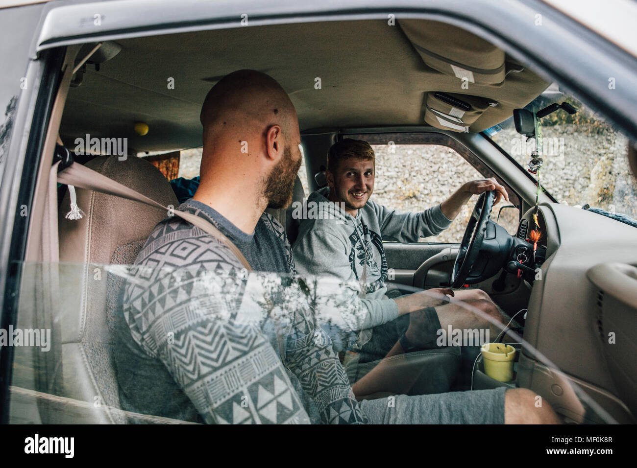 Zwei lächelnde junge Männer im Auto auf einer Straße Reise Stockfoto